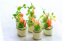 small potted plants with carrots and green leaves in them on a white surface