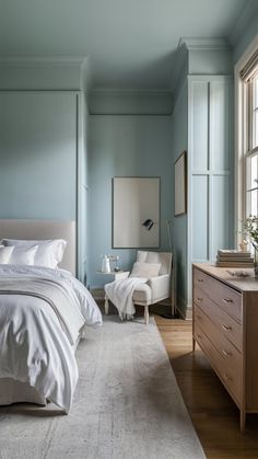 a bedroom with blue walls and white bedding in the corner, along with two chairs