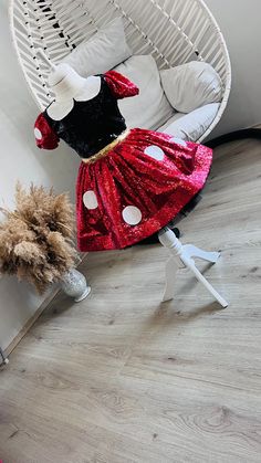 a minnie mouse costume sitting on top of a white chair next to a stuffed animal