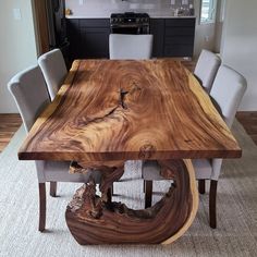 a wooden table with chairs around it in the middle of a living room and kitchen area