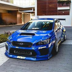 a blue subarunt parked in front of a building