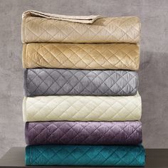 four blankets stacked on top of each other in different colors and patterns, with one folded over the edge