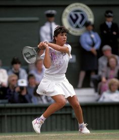 a woman swinging a tennis racquet on top of a tennis court in front of a crowd