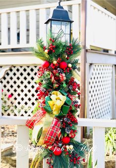 a christmas wreath on top of a white fence next to a light pole with a lantern