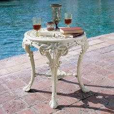 a table with two glasses on it next to a pool