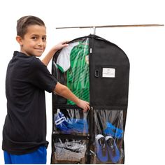 a young boy standing next to a black bag with clothes in it and holding onto the back