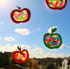 paper apples are flying in the air with colored papers on them and one has an apple cut out