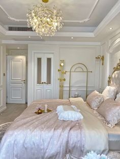 a bedroom with a chandelier hanging from the ceiling and two pillows on the bed