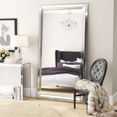 a large mirror sitting on top of a wooden floor next to a chair and table