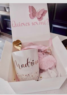 a pink teddy bear sitting in a white box next to a coffee mug with the words quilces somi on it