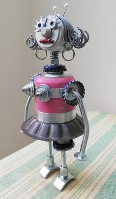 a metal robot with pink and silver dress sitting on top of a striped table cloth