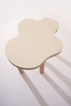 a white table sitting on top of a hard wood floor next to a wall with shadows coming from it