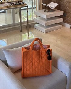 an orange purse sitting on top of a white couch