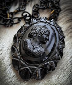 Circa 1920's bakelite, hand carved black mourning cameo necklace picturing a striking young woman's profile with a scalloped pie crust rim.  It measures 3" x 2-3/8". Victorian Black Medallion Jewelry, Black Victorian Medallion Jewelry, Black Cameo Medallion Jewelry, Victorian Medallion Necklace With Carved Details, Antique Black Necklace With Large Pendant, Victorian Carved Medallion Necklace, Victorian Medallion Carved Necklace, Vintage Black Cameo Jewelry, Vintage Black Cameo Necklace