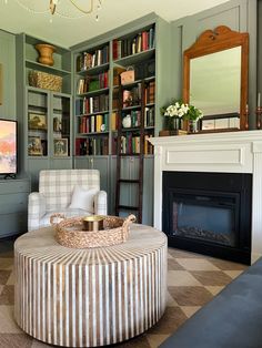 a living room filled with furniture and a fire place in front of a book shelf