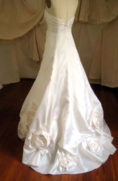 a white wedding dress on display in front of curtains