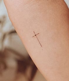 a small cross tattoo on the arm