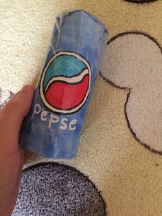 a hand holding a can of pepsi on the floor with mickey mouse ears drawn on it