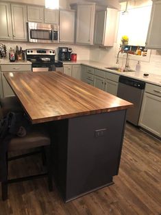 a kitchen with an island in the middle and stainless steel appliances on the other side