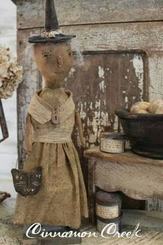 an old fashioned doll is standing next to some jars and other items on a table