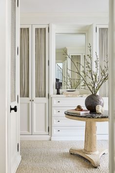 a room with white cabinets and a round table in the center, along with a vase filled with flowers