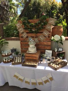 a table topped with cakes and cupcakes under a wooden sign