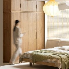 a woman walking past a bed in a bedroom