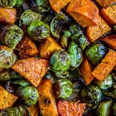 roasted brussel sprouts and sweet potatoes on a baking sheet with a fork