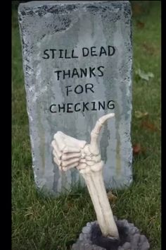 a tombstone with a hand holding a bone in it that says, still dead thanks for checking