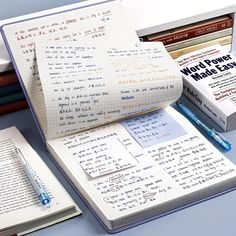 an open notebook with writing on it next to several books and a blue ballpoint pen