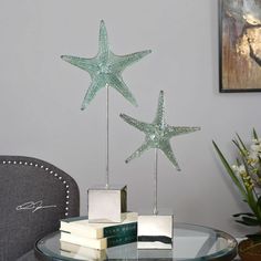 three glass starfishs sitting on top of a table next to books and a vase