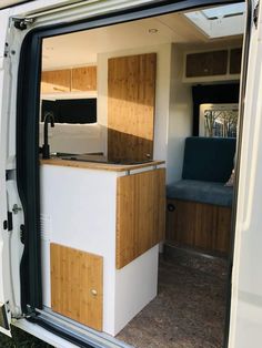 the interior of a camper with wood paneling and white walls, open door