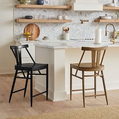 two wooden chairs sitting next to each other in a kitchen with open shelving on the wall