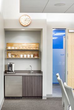 a kitchen with a clock on the wall next to a counter and chairs in front of it