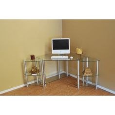 a glass desk with a computer on top of it in front of a yellow wall