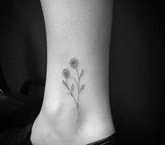 a black and white photo of a flower tattoo on the side of a woman's foot