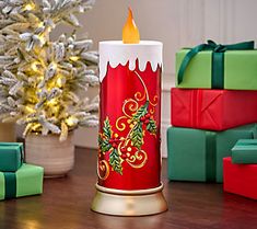 a lit candle sitting on top of a wooden table next to presents and a christmas tree