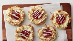 small pastries with jelly on them sitting on a wooden tray