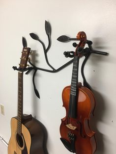 two guitars are hanging on the wall next to each other and one is holding a violin