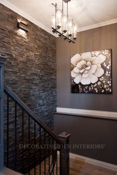 a painting hanging on the wall next to a stair case with chandelier above it