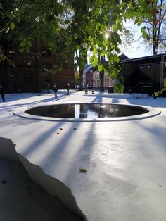 the sun shines through some trees and onto a water feature in front of a building