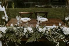 the table is set with white flowers and greenery