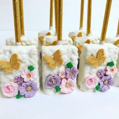 four vases with flowers and butterflies on them sitting next to each other in front of candles