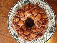 a bundt cake covered in nuts and sauce on a floral plate with a wooden table