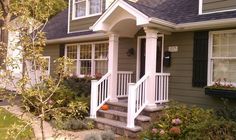 a small house with white trim and black shutters on the front door, steps leading up to the porch