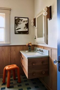 a bathroom with an orange stool next to the sink