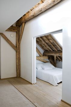 an attic bedroom with white bedding and wooden beams