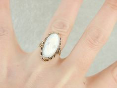 "This vintage ring is crafted in wonderful tones of yellow and creamy white! 14K yellow gold comprises the frame, while the cameo at the center is carved from pale, barely blush pink conch shell. This unusual piece is timeless, likely made in Italy in the mid-1900's Metal: 14K Yellow Gold Gem: Pink Shell Cameo Gem Measurements: 19.1 x 9.2 mm, Oval Ring Size: 5.75 Marks: \"14K\" Stamped on the inside band SKU #: 0CLA3D-N Each piece has been identified and graded by a Graduate Gemologist who has b Antique Cocktail Ring, Oval Ring, Oval Rings, Conch Shell, Pink Blush, Vintage Ring, Creamy White, Conch, Cocktail Ring