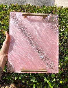 a hand holding up a piece of pink marble with gold trimmings on it