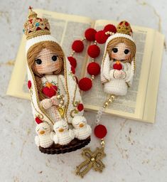 two little dolls are sitting on top of an open book with tassels around them